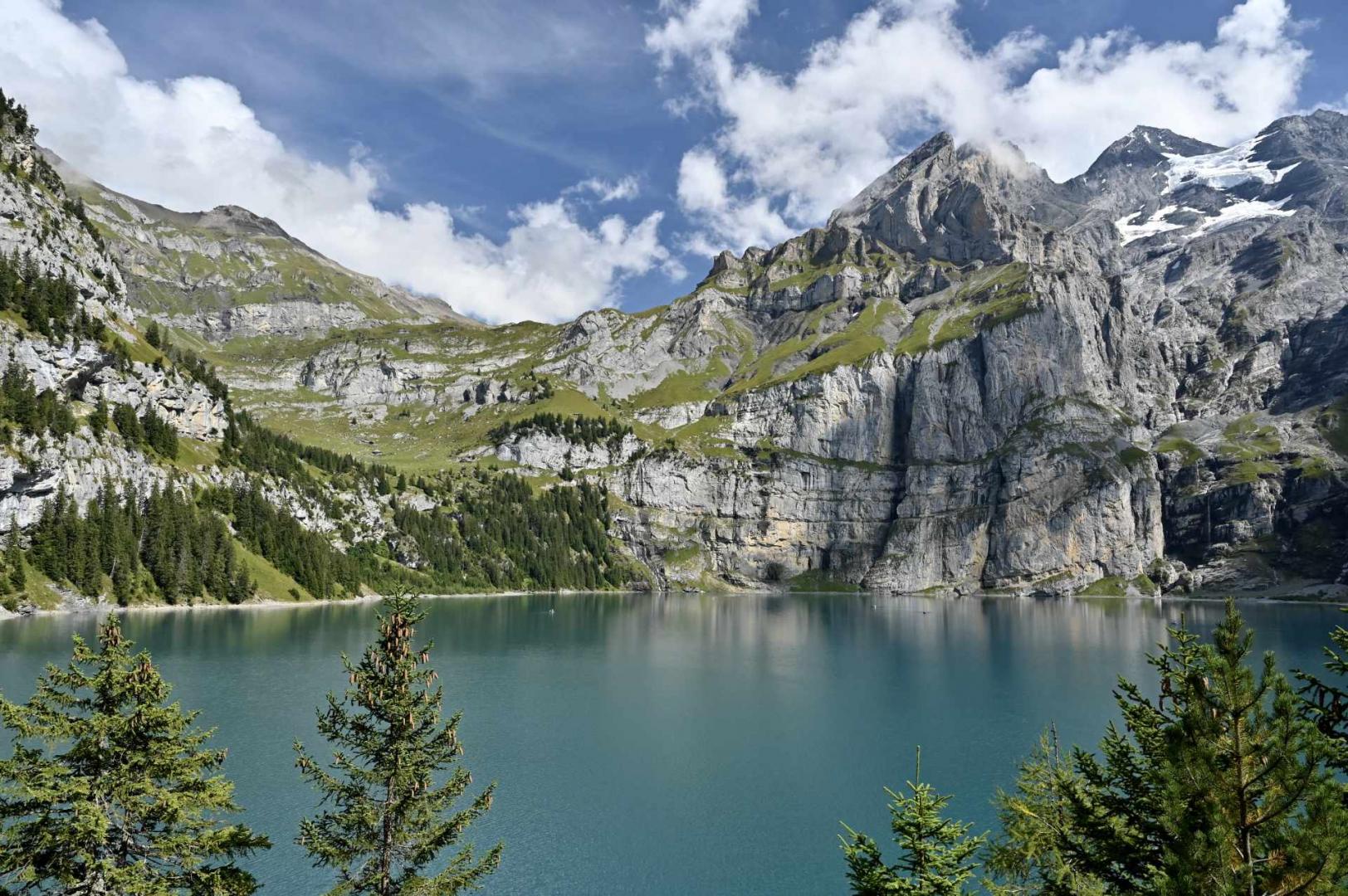 A serene lake in Switzerland with mountains and clouds above